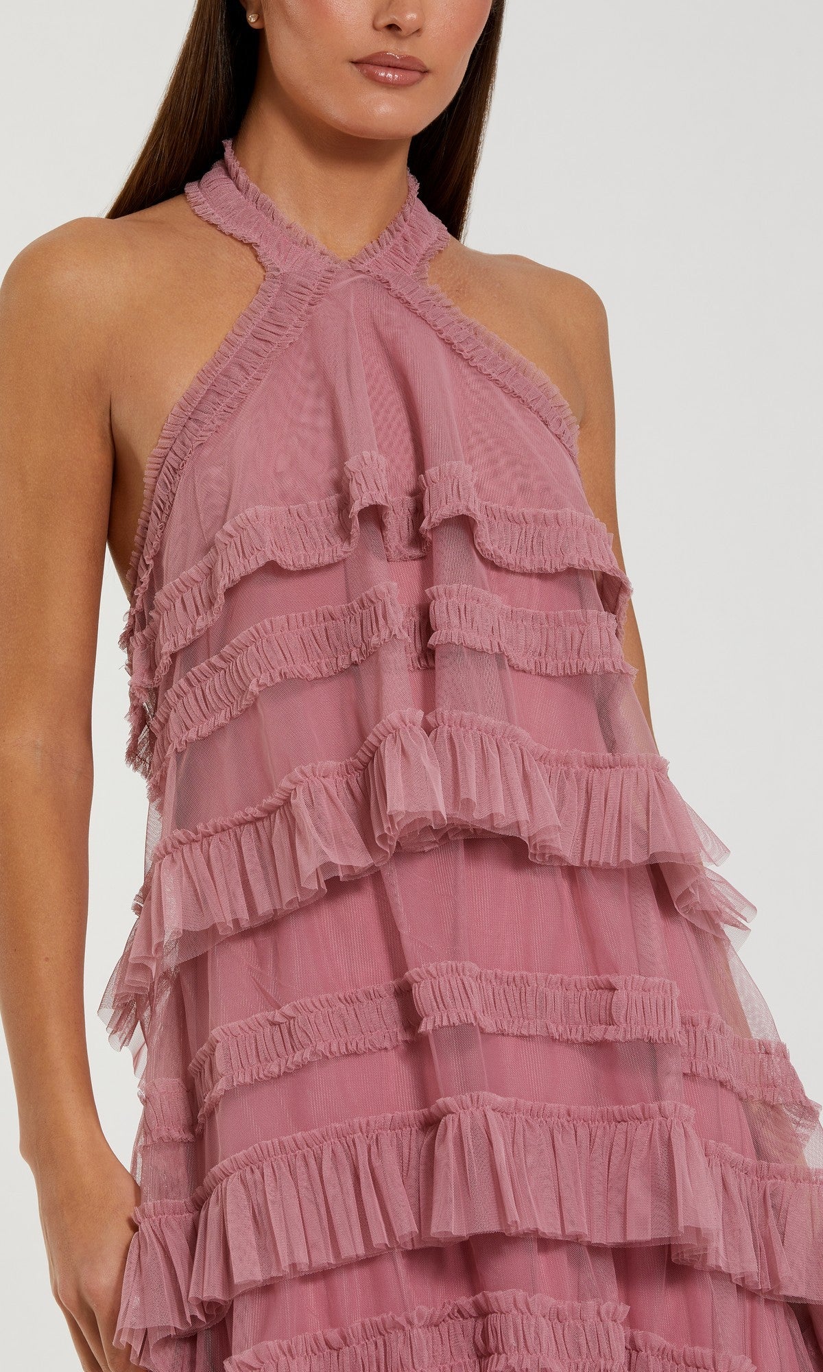 A woman wearing the Mac Duggal 8276 Tea-Length Party Dress, a sleeveless halter mesh ruffle dress featuring multiple layers of pink fabric and a chic high-low hemline, stands against a plain background.